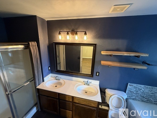 A bathroom with a double sink vanity and a mirror above it.