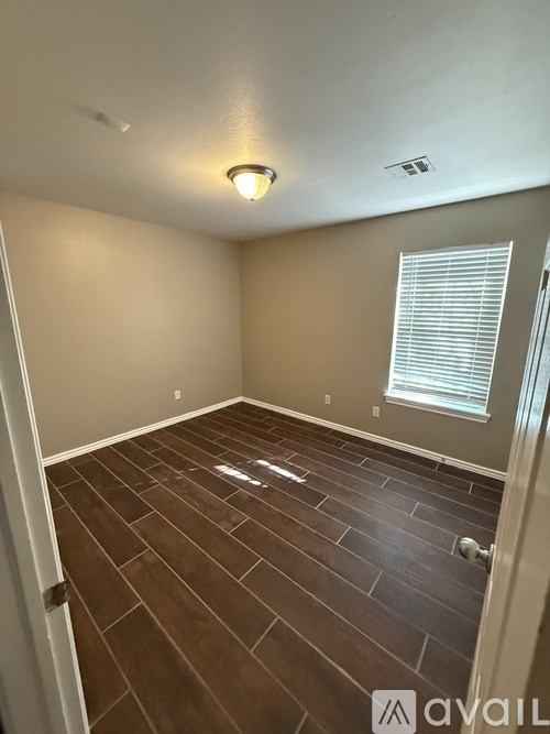A room with wooden flooring and a window with blinds.