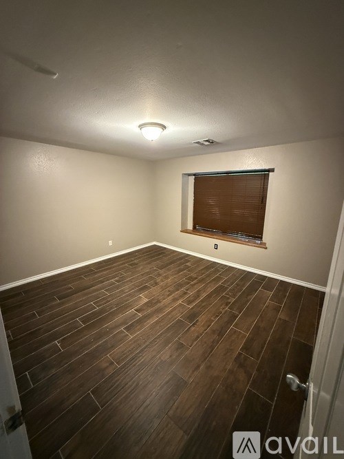A room with wooden flooring and a window with blinds.