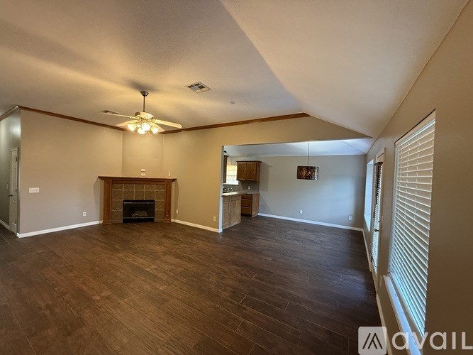 A spacious living room with wood flooring and a fireplace.