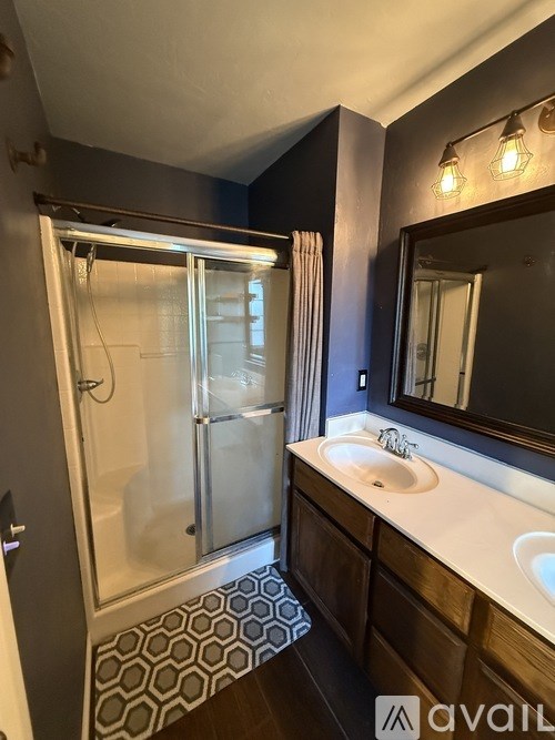 A bathroom with a sink, mirror, and shower.