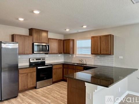 A kitchen with wooden cabinets and a black countertop.