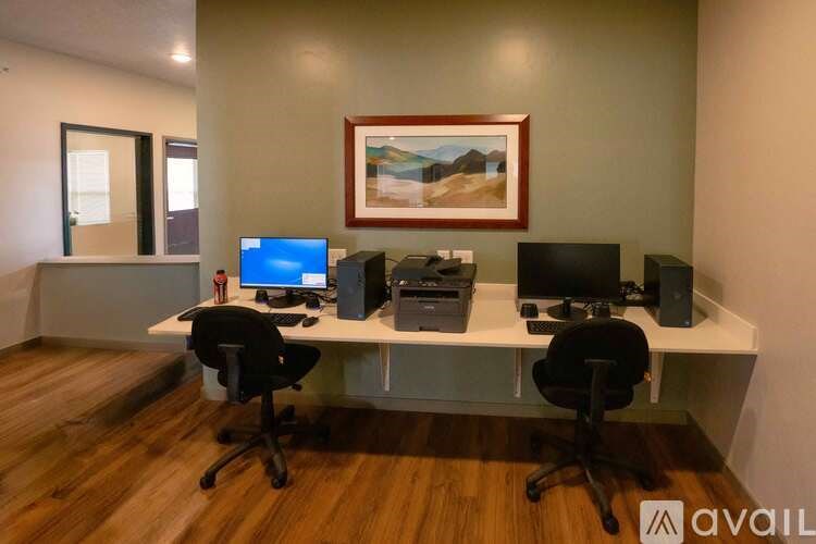 A room with a desk, two chairs, and a painting on the wall.