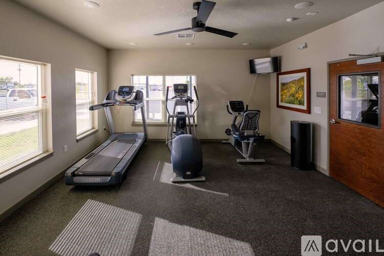 A gym room with a treadmill, elliptical trainer, and a stationary bike.