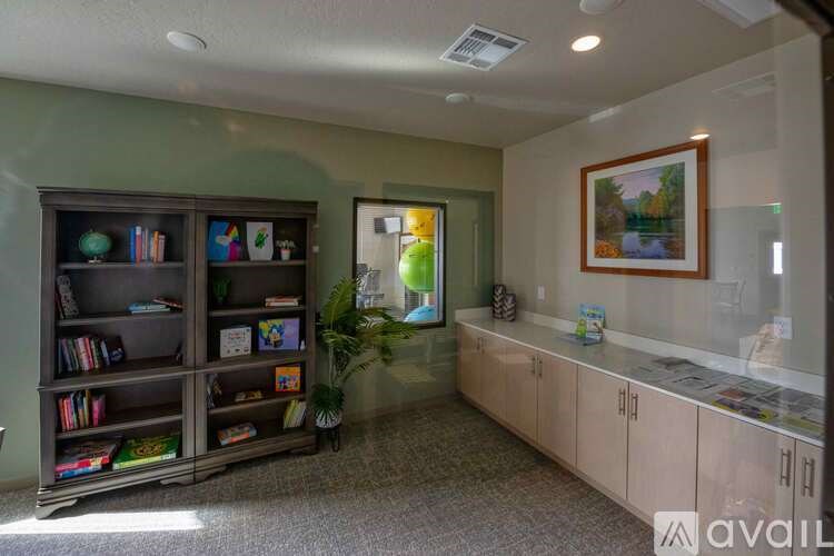 A room with a bookcase, a potted plant, and a framed picture on the wall.