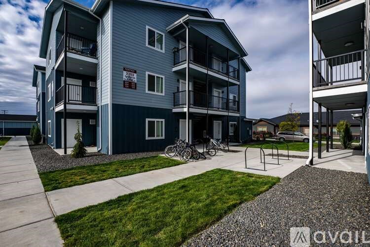 A modern apartment complex with a blue building and a bicycle parked in front.