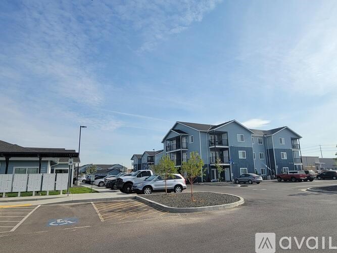 A parking lot with a building in the background and a car parked in the spot with a handicap sign.