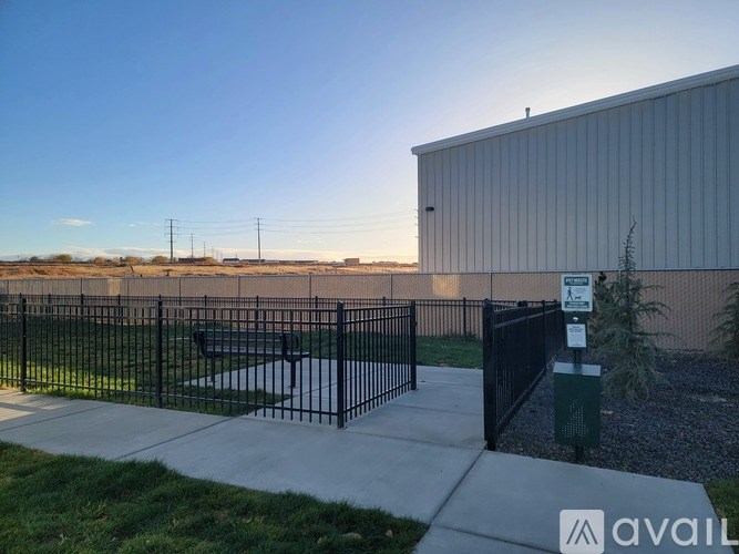 A metal fence surrounds a small park area with a sign in front of a building.