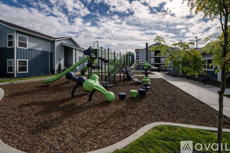 A playground with a green slide and a brown mulch area.