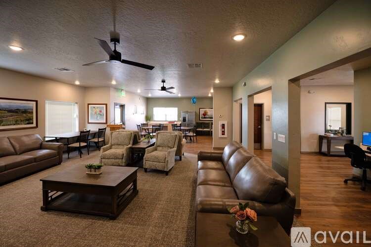 A spacious living room with brown leather furniture and a ceiling fan.
