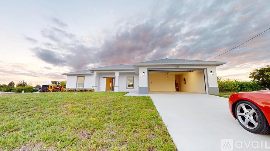 A modern house with a red car parked in front.