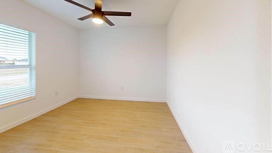 Empty room with a ceiling fan and wooden floor.