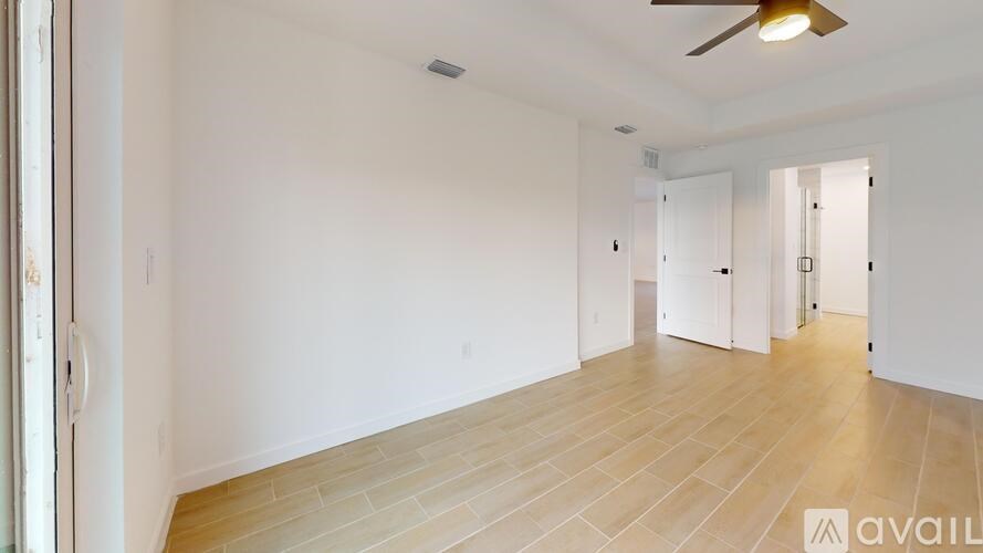 A spacious room with wooden flooring and white walls.