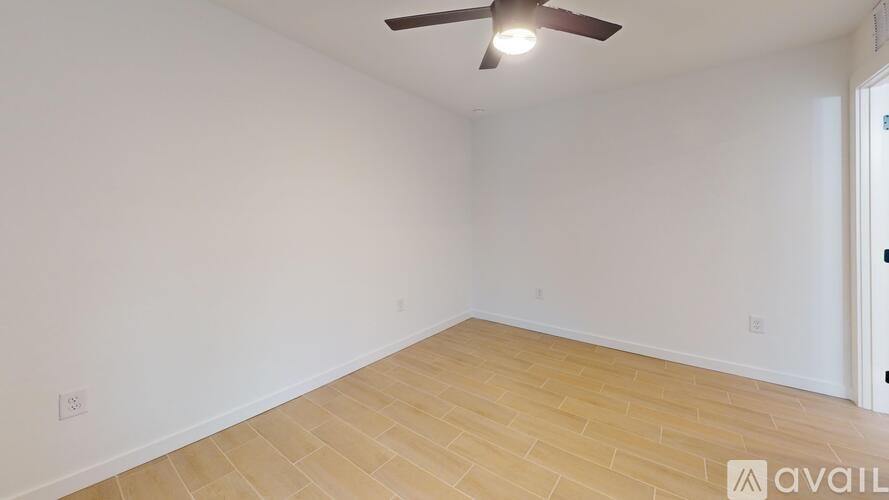 A room with a ceiling fan and wooden flooring.