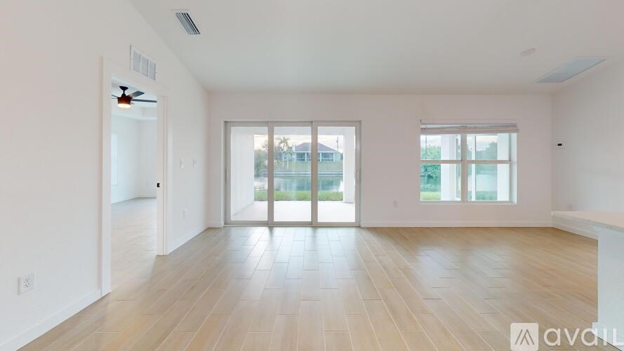 A spacious room with wooden flooring and a sliding glass door.