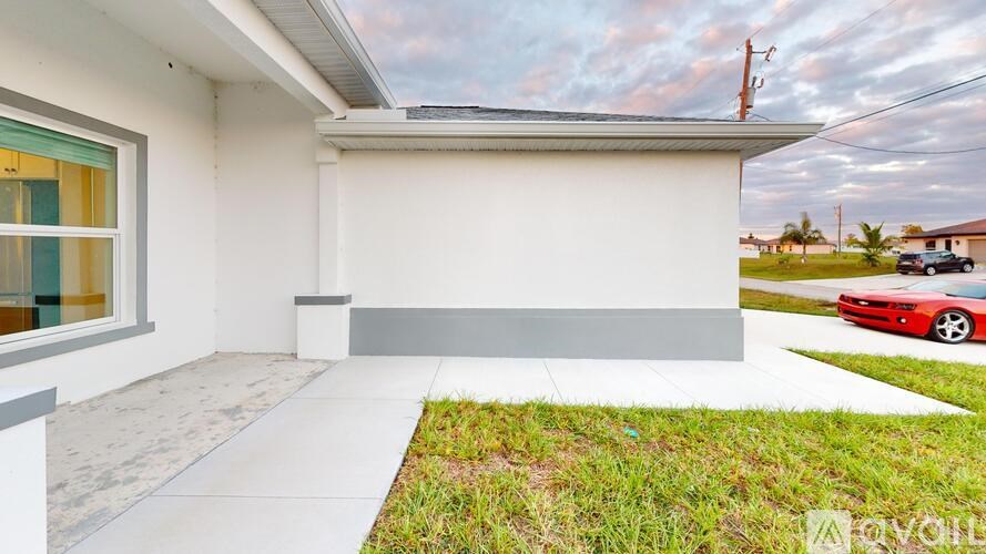 A modern house with a red car parked in the driveway.
