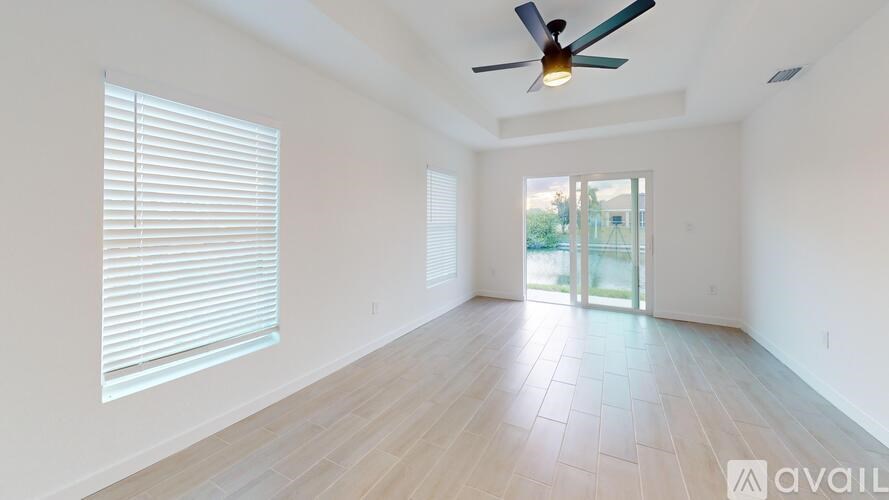 A room with a ceiling fan and sliding glass doors.