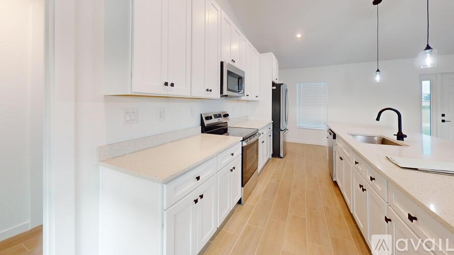 A kitchen with white cabinets and a wooden floor.