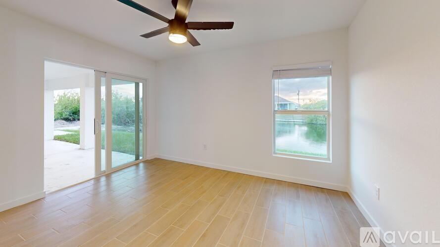 A room with a ceiling fan and sliding glass doors.