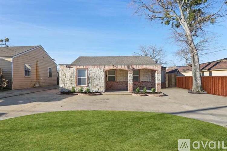 A house with a stone wall and a tree in front.