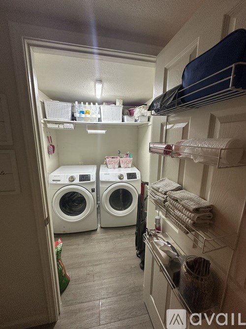A laundry room with a washer and dryer and a shelf with towels.