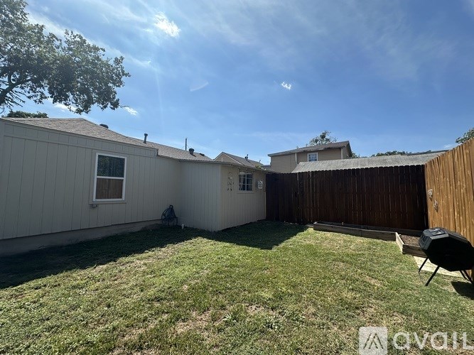 A backyard with a wooden fence and a small patio area.