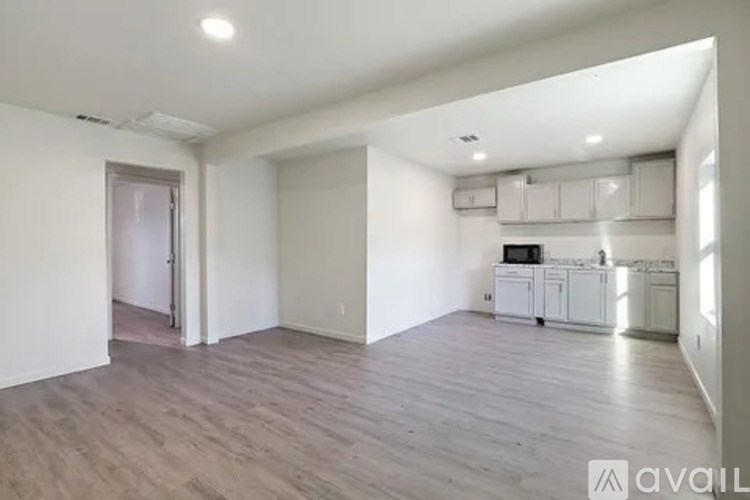 A spacious living room with a kitchen area in the background.