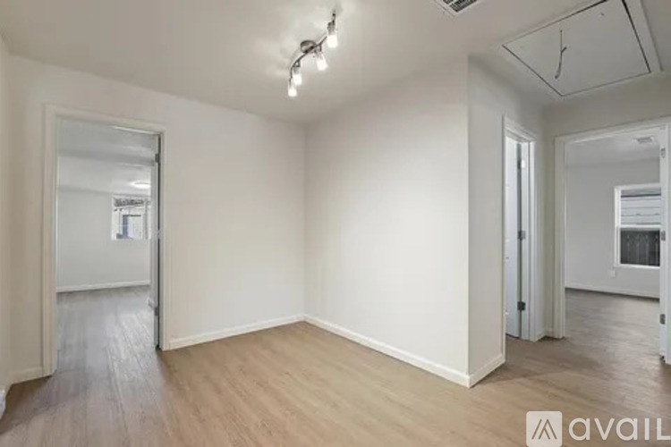A room with wooden flooring and white walls, with a door on the left and another door on the right.