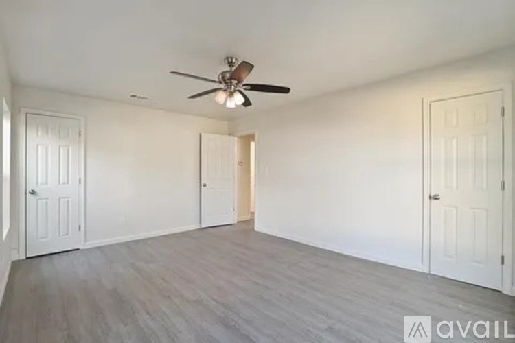 A room with a ceiling fan and wooden flooring.