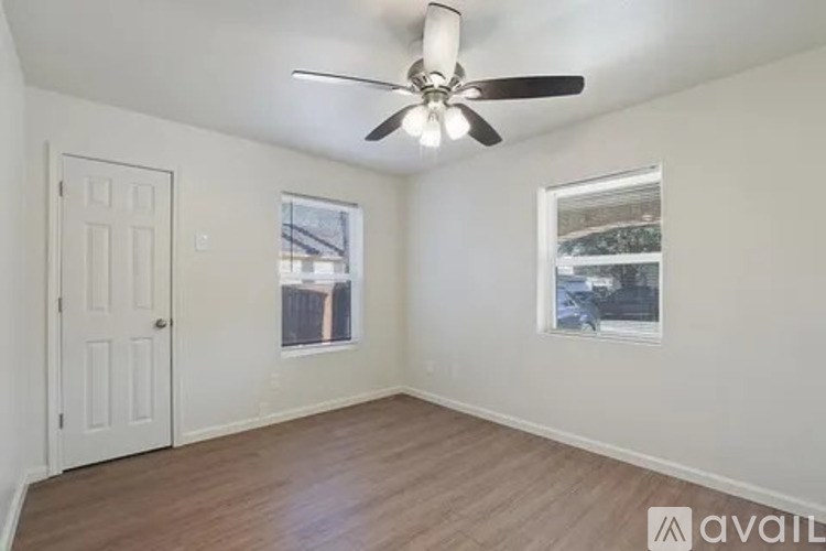 A room with a ceiling fan and two windows.
