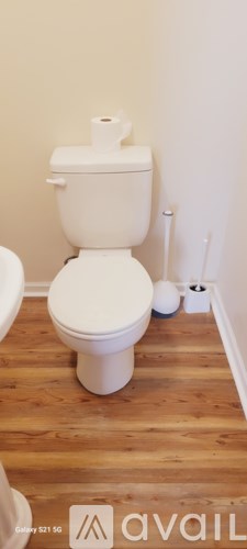A white toilet with a roll of toilet paper on top.
