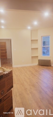 A room with wooden floors and a window with a radiator to the side.