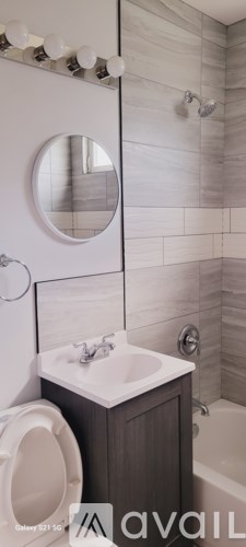 A bathroom with a white sink and a round mirror.