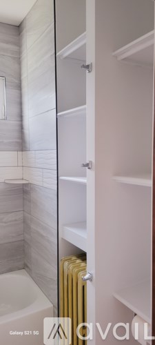 A bathroom with a white tub and a white shelving unit.