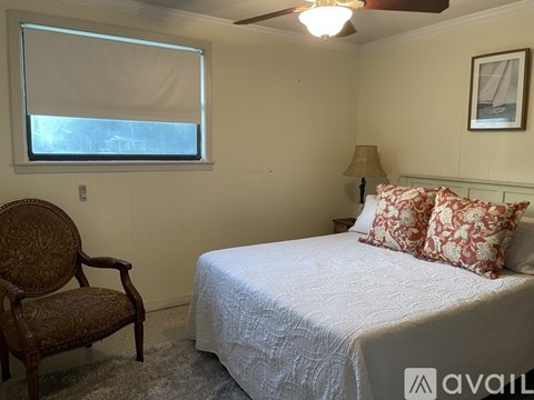 A bedroom with a bed, chair, and window.