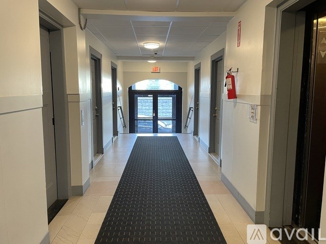 A hallway with a black carpet and white walls.