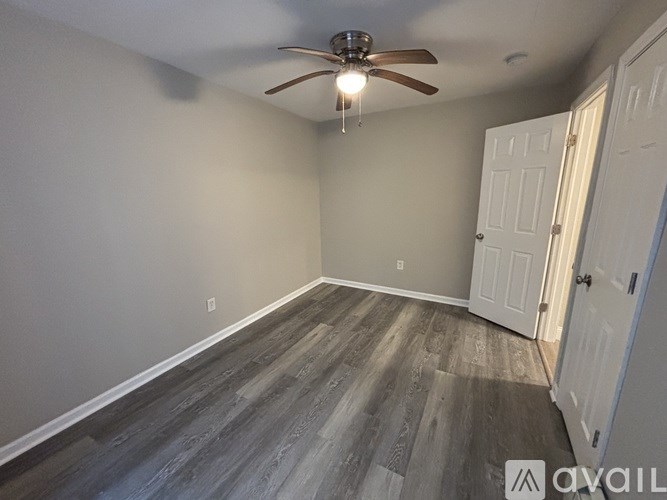 A room with a ceiling fan and wood flooring.