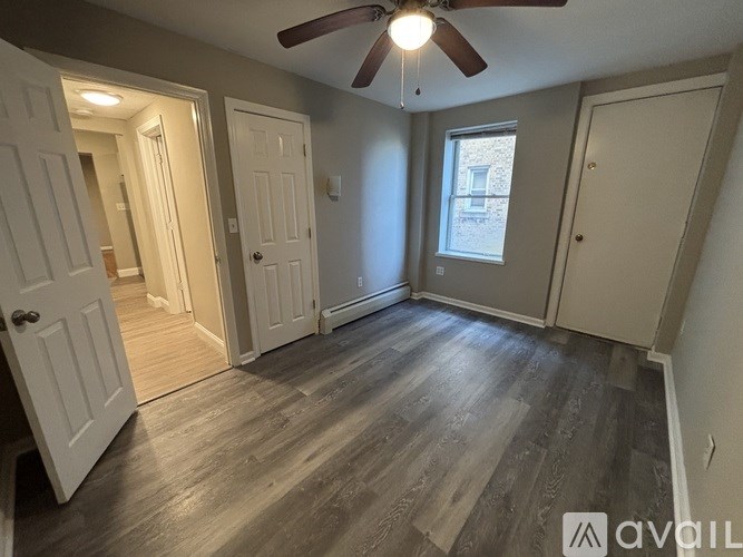 A room with a ceiling fan and wooden flooring.