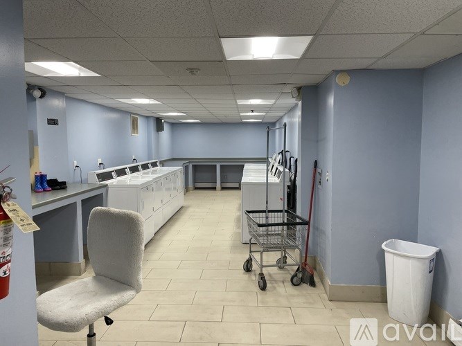 A clean, empty room with a white chair and a white trash can.