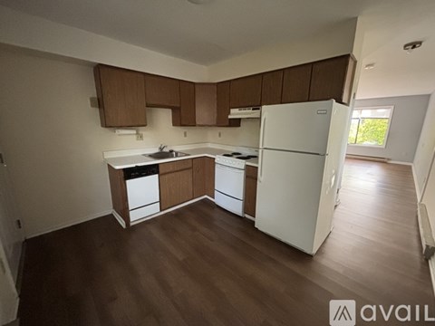 A kitchen with white appliances and wooden cabinets.