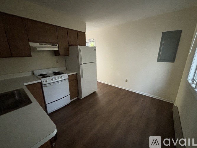 A kitchen with white appliances and brown cabinets.
