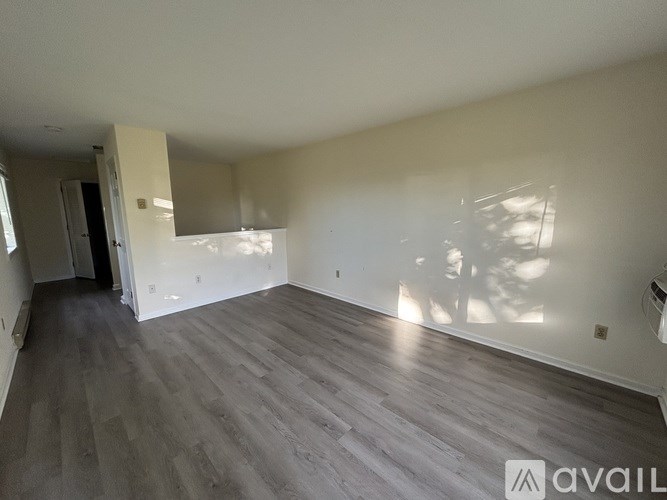 A room with wooden flooring and white walls is available for rent.