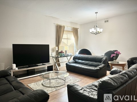 A living room with black leather furniture and a flat screen TV.