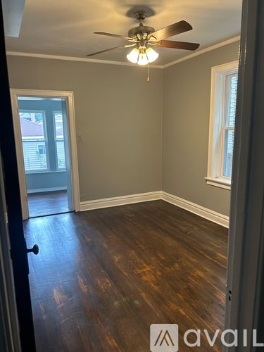 A room with a ceiling fan and wood flooring.