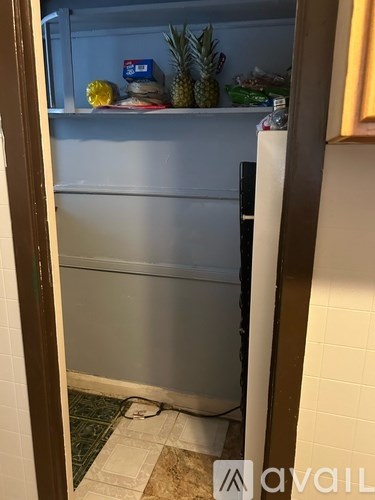 A refrigerator with a pineapple on top and a box of milk on the door.