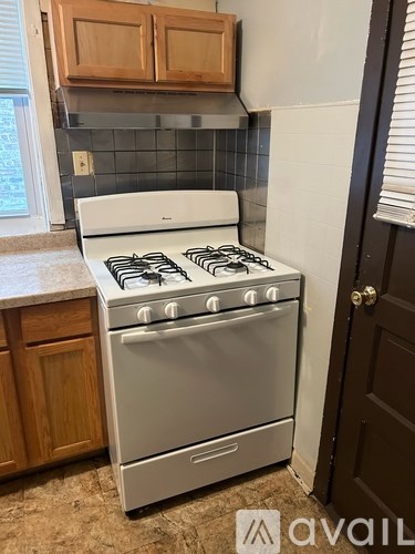 A white gas stove with four burners and two ovens is in a kitchen.