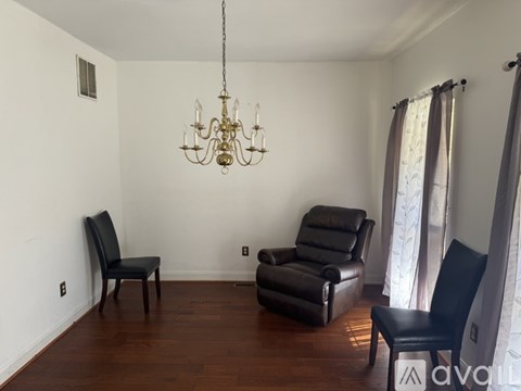 A living room with a chandelier, two chairs and a couch.