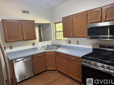 A kitchen with wooden cabinets and a stainless steel dishwasher.