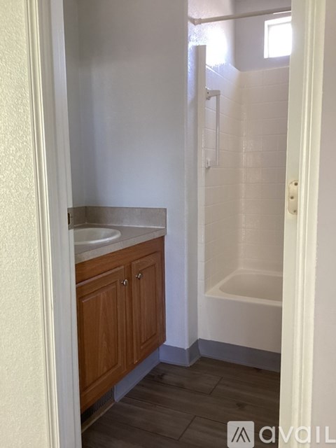 A bathroom with a white tub and wooden cabinets.