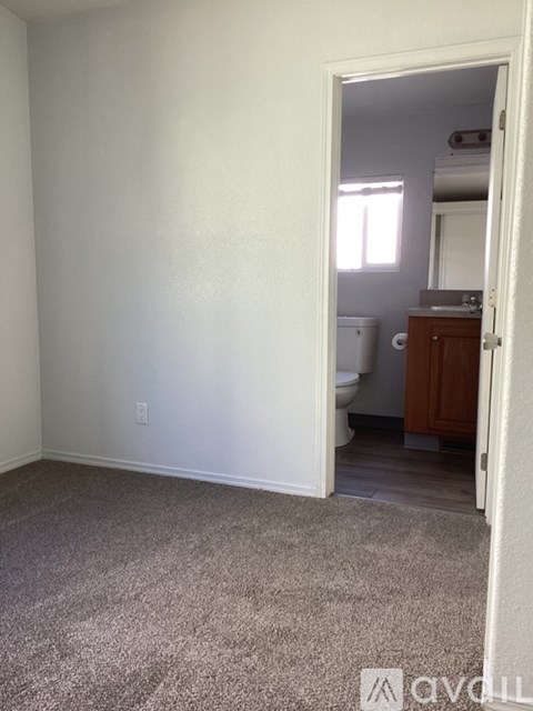 A room with a carpeted floor and a doorway leading to a bathroom.